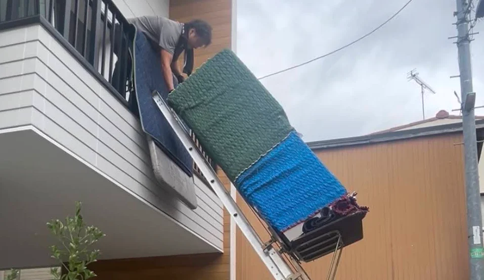 住宅の2階ベランダへ大型家電を搬入する電動はしごの全景